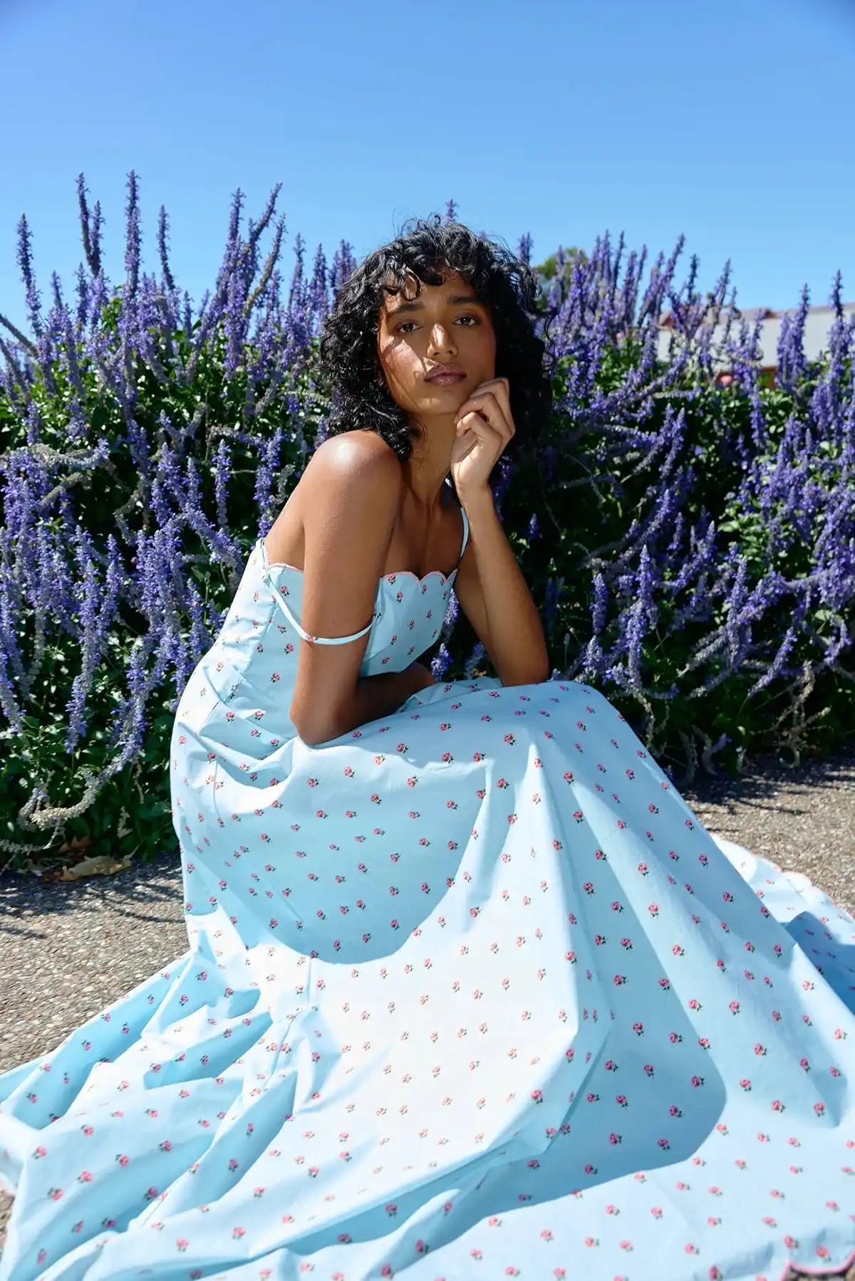 Woman in a light blue floral print maxi dress with a scalloped neckline.